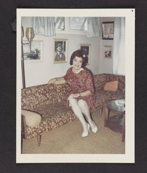 [Sitting on the couch in a pink patterned dress, location unknown]
