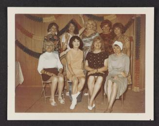 [Kathey, Susanna, Jody, Ann, Lili, and four friends posing in front of decorations, location unknown]
