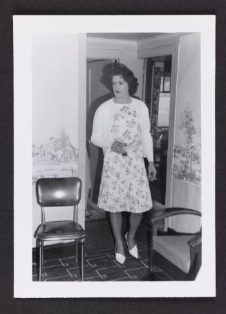 [Holding a cigarette and a drink in a floral dress, Chevalier d’Éon, Hunter, NY]
