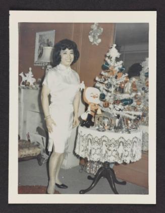 [Lili beside a small Christmas tree in Susanna and Marie’s New York City apartment]
