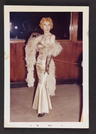 [Red head in a shiny dress and boa, location unknown]
