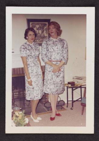 [Sheila with her wife, Avi, standing by the fireplace in matching dresses, Casa Susanna, Hunter, NY]

