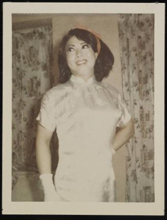 [Lili with a red ribbon in her hair, wearing a white silk dress, location unknown]
