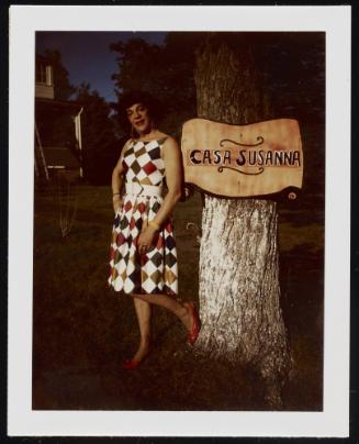 [Susanna in a checkered dress standing beside the 'Casa Susanna' sign, Hunter, NY]
